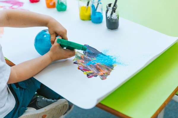 El arte en la infancia. Niño pintando con pinceles y colores brillantes