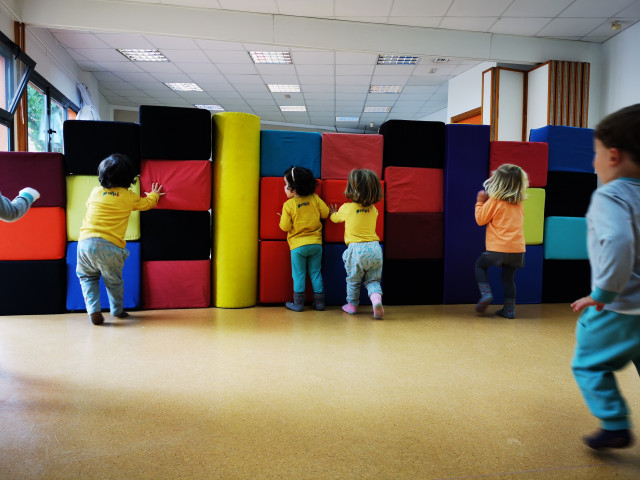 Niños derribando un muro en la sala de psicomotricidad de la Escuela Infantil EMPI en Murcia, desarrollando habilidades motoras y trabajo en equipo.